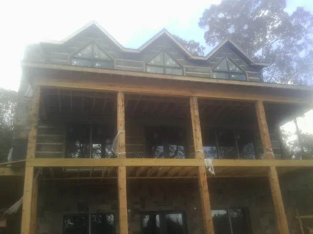Dormers and porch framing on a large log home under construction — Roof Coating work by our crew in Martinsville